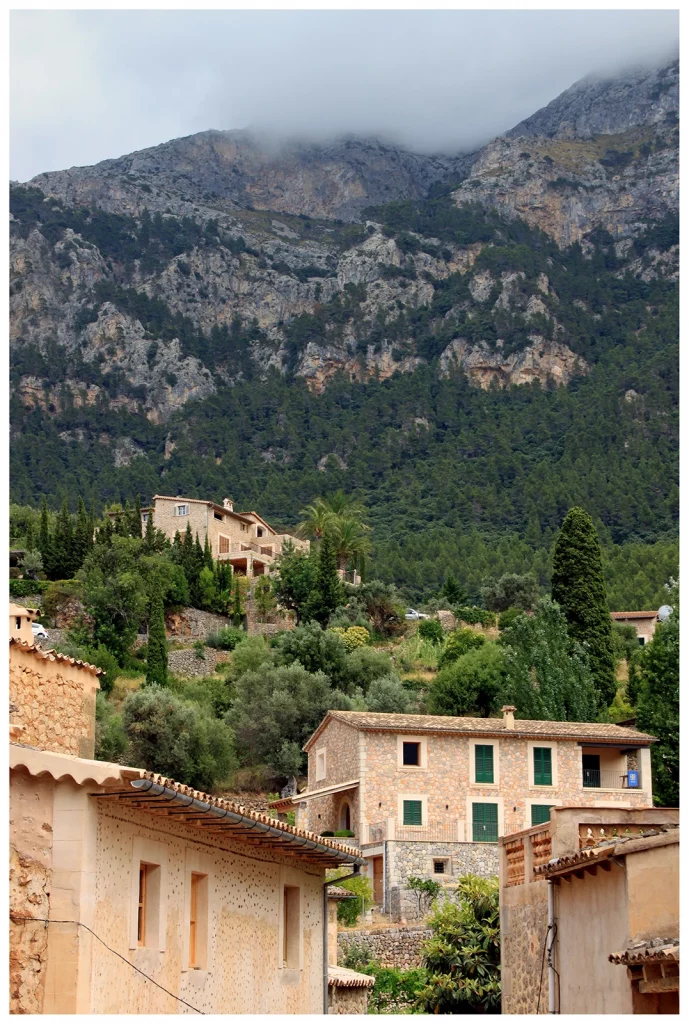 Deià in the Tramuntana mountains of Mallorca with stone houses beneath dramatic cliffs
