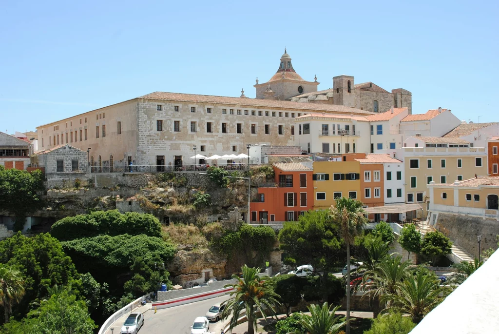 This image displays the iconic cliffside view of the historic centre of Mahón (Maó), the capital city of Menorca, Spain